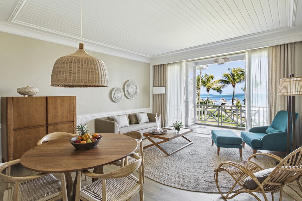 Wohnbereich der Senior Suite Sea View im Heritage Le Telfair mit Holztischgarnitur, türkisfarbenem Sessel und Meerblick