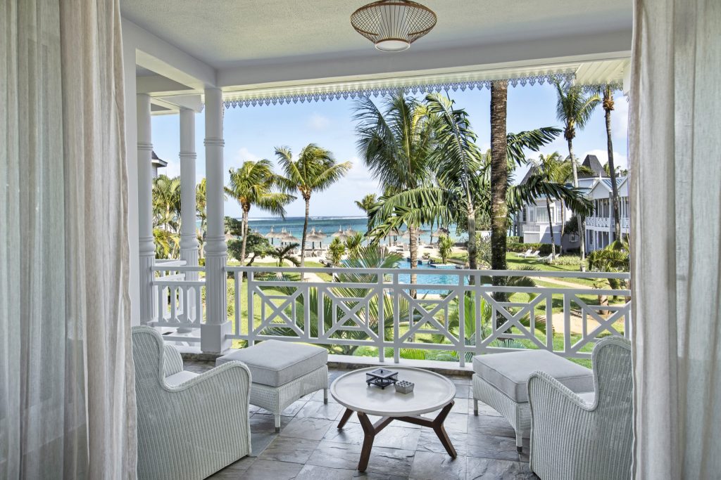 Veranda der Senior Suite Sea View mit weißen Sesseln, Holztisch und Blick auf Garten, Pool und Meer in Mauritius