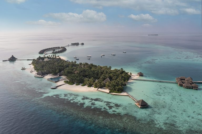 Luftaufnahme des Huvafen Fushi Resorts mit Wassersportbereich, Infinity-Pool und Pfahlbauten auf den