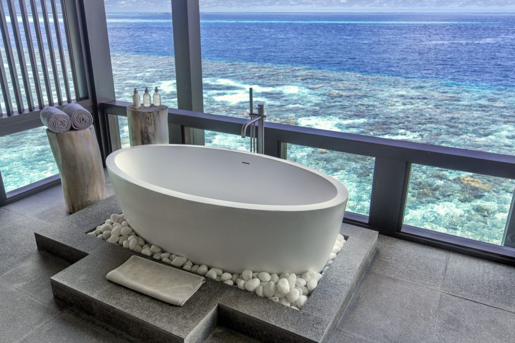 Freistehende Badewanne im Sulha Spa mit Glaswänden und Meerblick auf Kudadoo Private Island Malediven