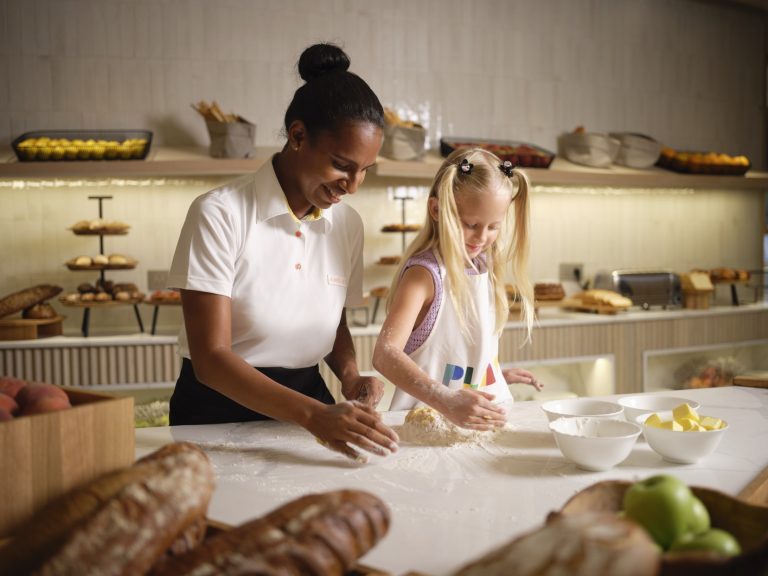 Bäckerei im Lux Belle Mare mit zwei Personen, die Teig an einem langen Holztisch formen, Brote und Gebäck im Hintergrund