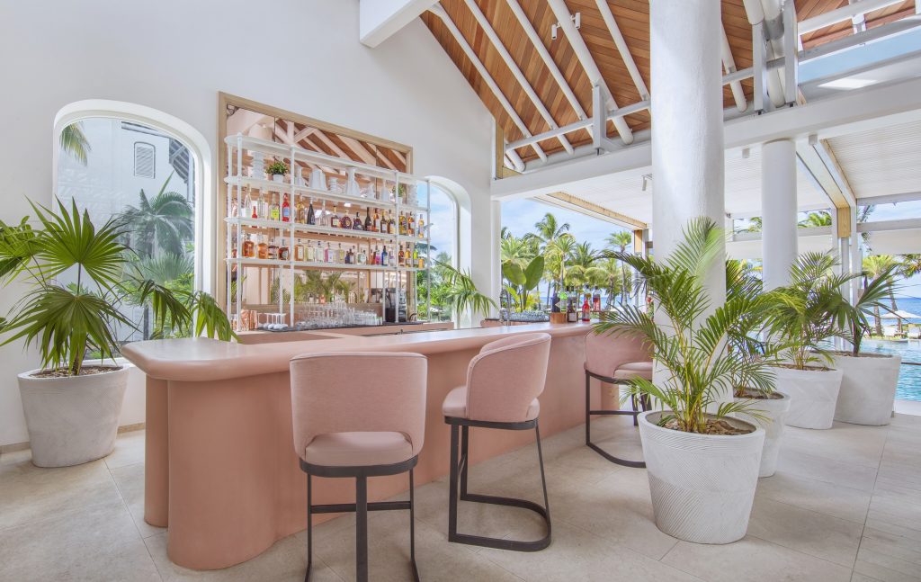 Offene Hotelbar Lux Belle Mare Bar Aperitivo mit weißen Säulen, rosa Barhockern und tropischer Landschaft in Mauritius