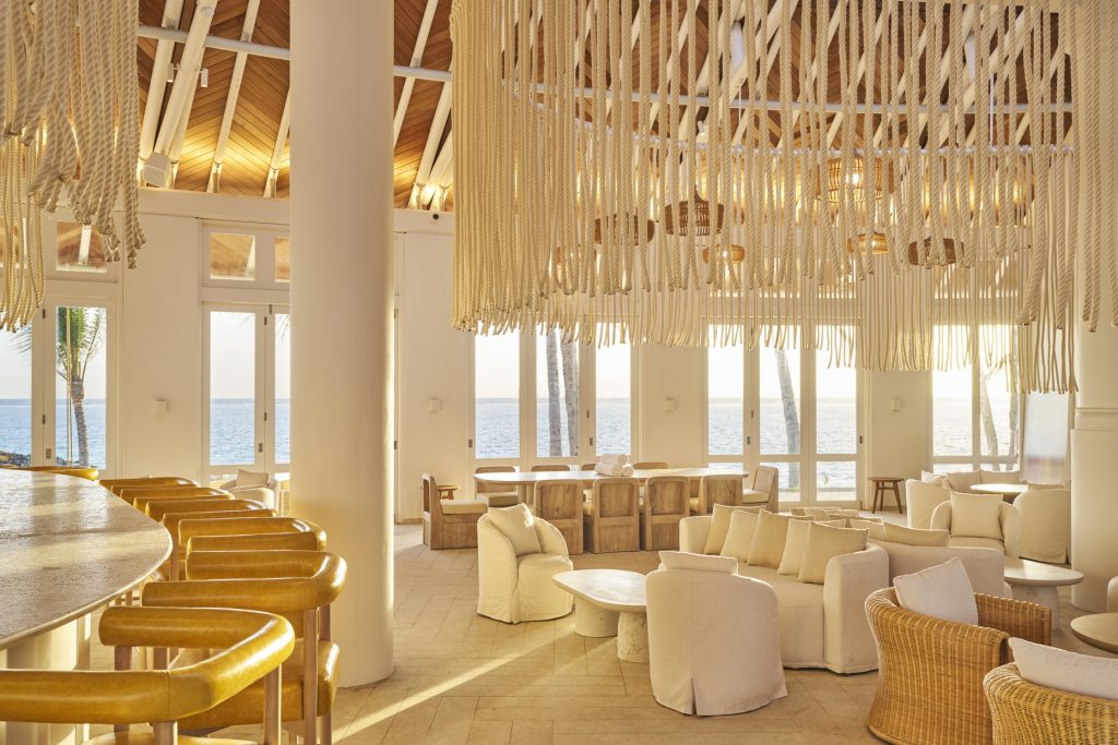 Innenraum der Bar Mixe im Lux Belle Mare mit großen Fenstern, Holzdecke, hellen Sesseln und Blick auf Meer und Palmen