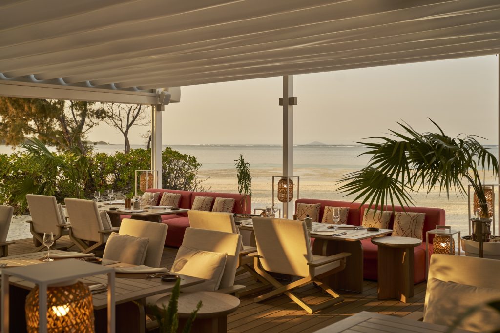 Offene Terrasse des restaurant-beach-rouge mit Holzplankenboden, roten Polstern und Blick auf das Meer in Mauritius