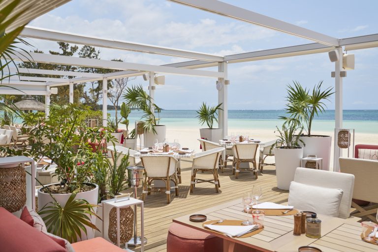 Offene Terrasse des Lux Belle Mare Restaurant Beach Rouge mit Holz- und Rattanmöbeln, Palmen und Blick auf Strand und Meer
