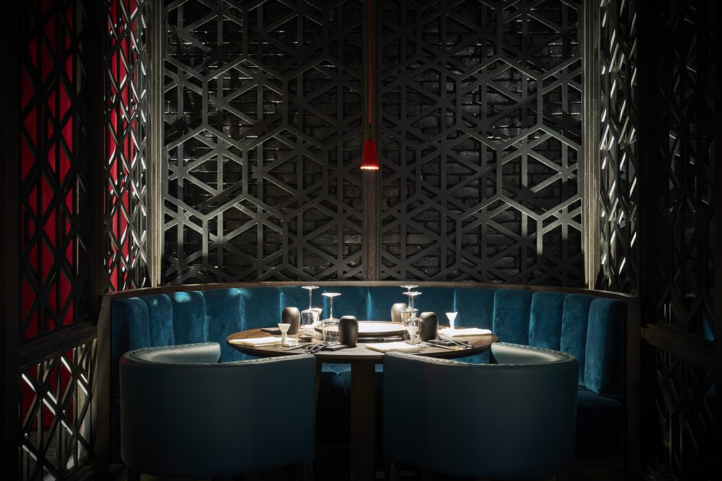 Halbrunde tiefblaue Samt-Sitzgruppe mit rundem Holztisch und gedecktem Geschirr im Restaurant Duck Laundry