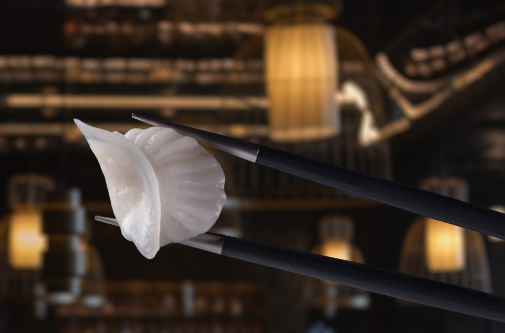 Dim Sum mit weißer Teighülle wird mit schwarzen Essstäbchen im Restaurant AI Kisu im Lux Grand Baie gehalten