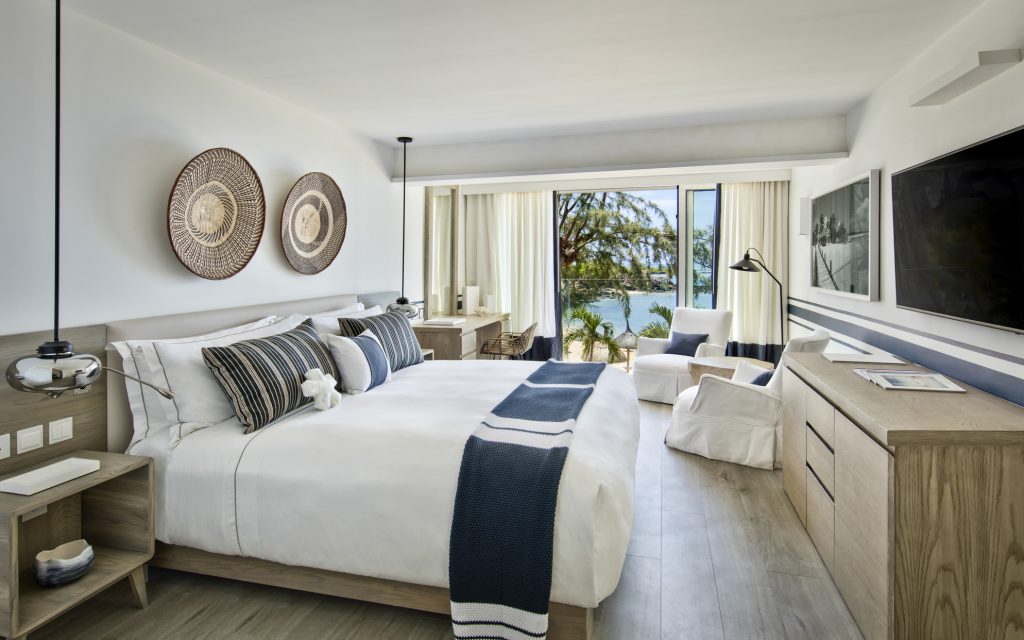 Modernes Lux Grand Gaube Family Suite Zimmer mit großem Bett, blauen Kissen und Küstenblick auf Mauritius