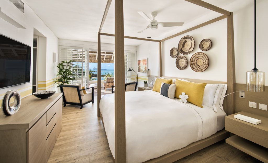 Ocean Junior Suite Zimmer mit hellem Holzboden, Himmelbett, geflochtenen Körben und Meerblick auf Mauritius