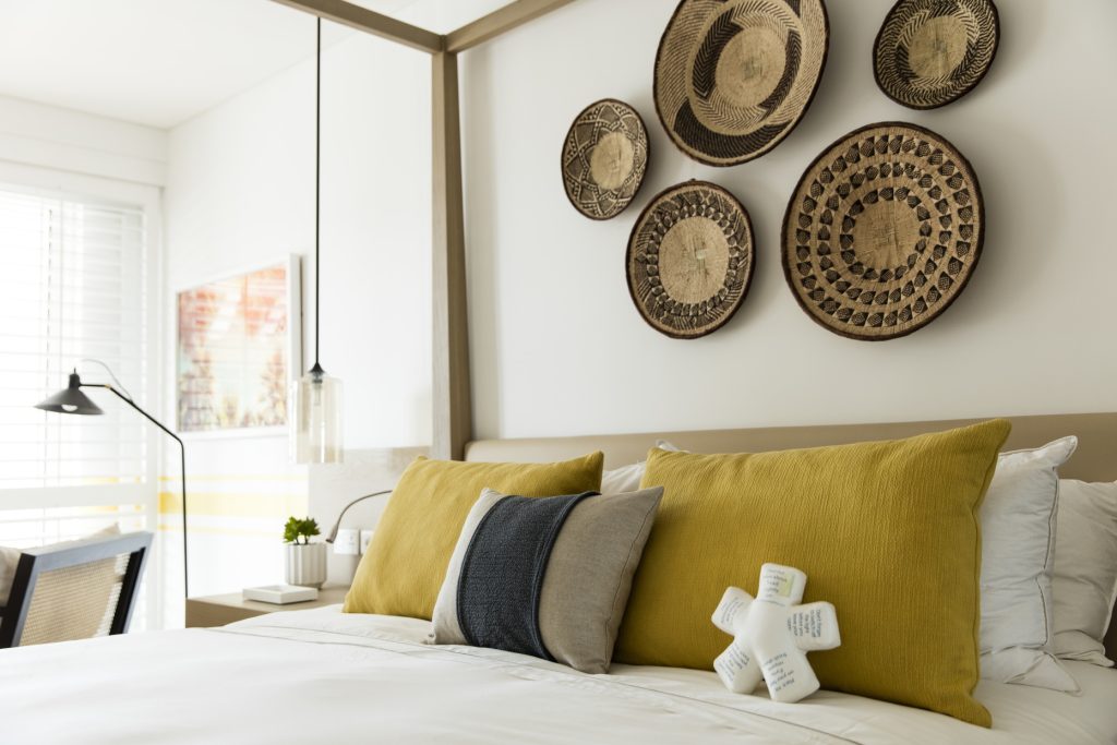 Modernes Hotelzimmer Lux Grand Gaube Ocean Junior Suite mit Bett, weißen Jalousien, dekorativen Körben und Tageslicht