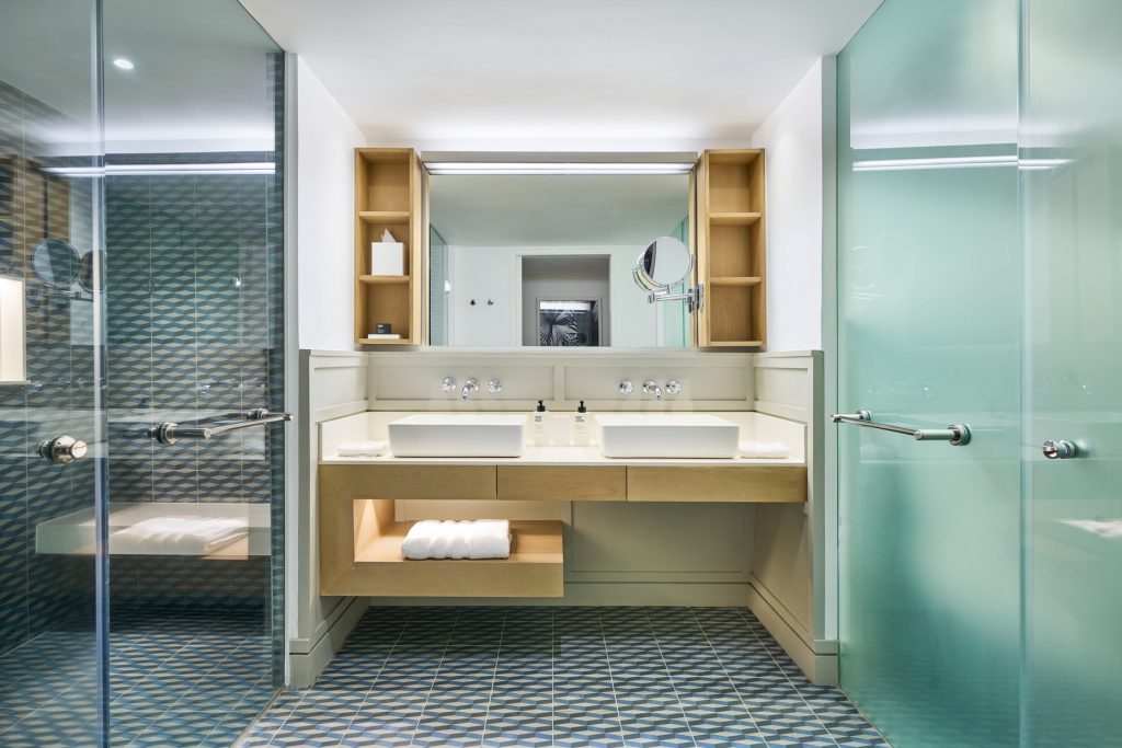 Modernes Badezimmer im Lux Grand Gaube Superior Room mit zwei quadratischen Waschbecken, Holzregalen und geometrischem.