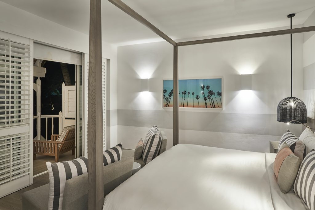 Junior Suite Zimmer Lux Grand Gaube mit Himmelbett, grauem Sofa, Kunstwerk und Veranda