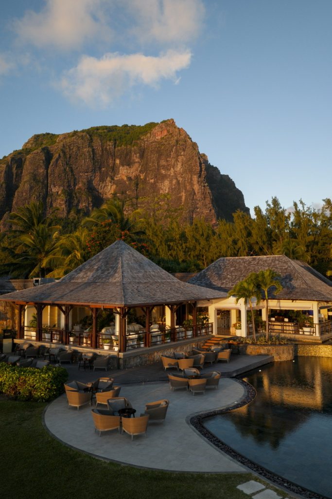 Poolterrasse mit geflochtenen Sitzgruppen, Holz-Stein-Architektur und Felsen im Hintergrund auf Mauritius