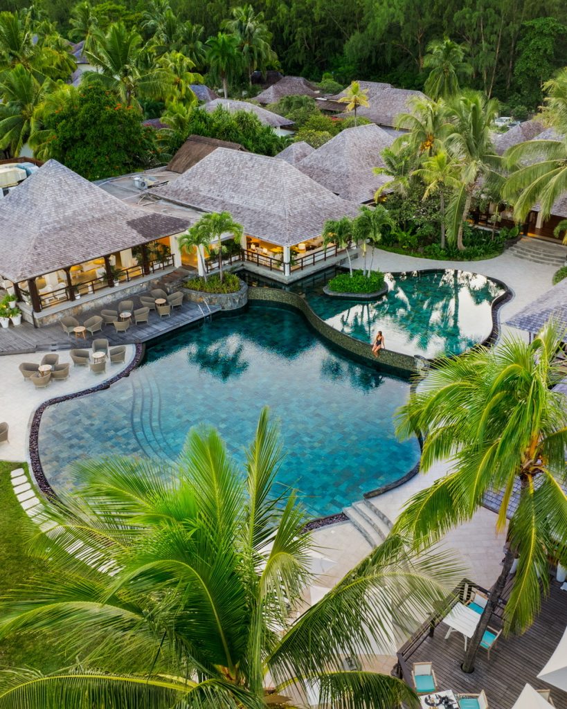 Vogelperspektive auf Lux Le Morne Pool mit organischer Form, Holzterrassen und grauen Dächern, Mauritius