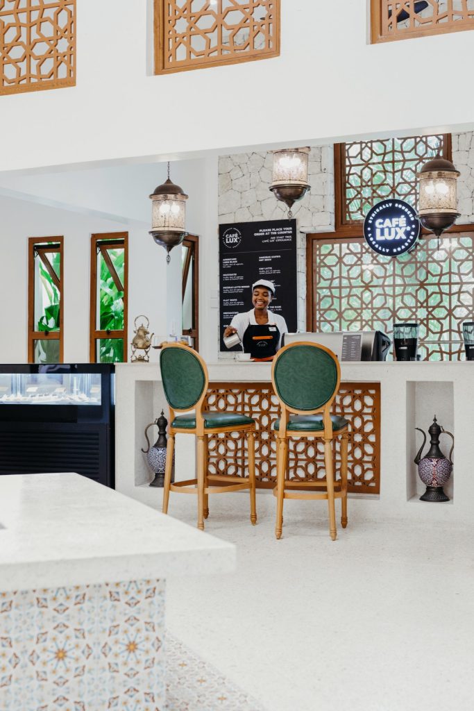 Cafébereich im Lux Marijani mit Holz-Barhockern, heller Steintheke und hängenden Laternenleuchten