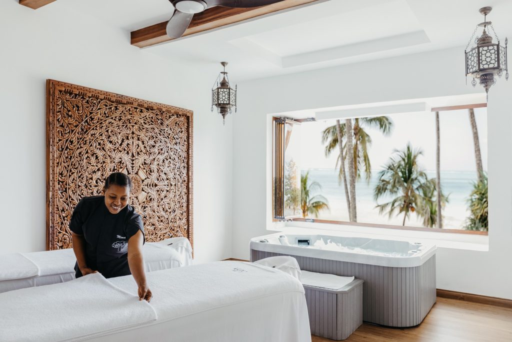 Wellness Spa im Lux Marijani mit zwei Massagetischen, Holzpaneel, Holzfußboden und Blick auf Palmen und Strand