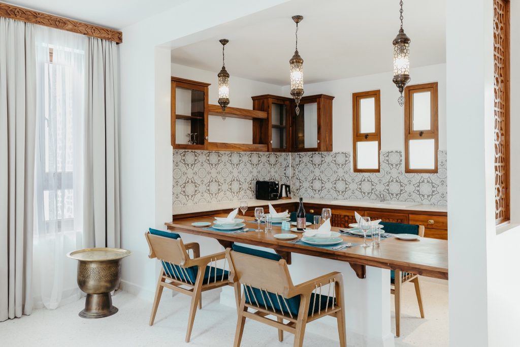 Moderne Küche im Lux Marijani mit Holztisch, blauen gepolsterten Stühlen, dekorativen Fliesen und Tageslichtfenster