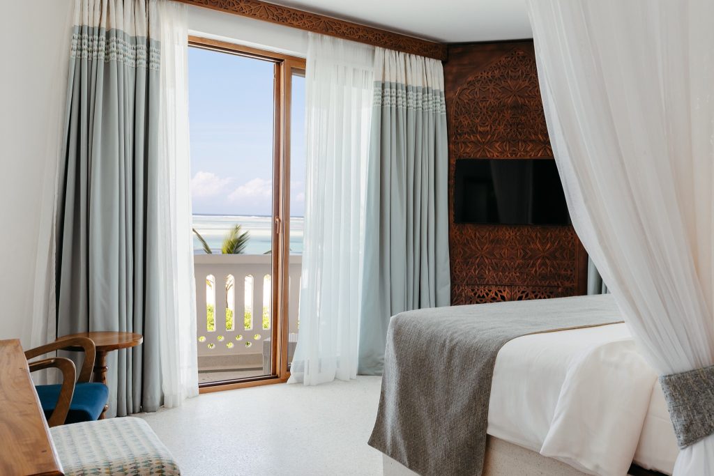 Hotelzimmer im Lux Marijani mit großem Bett, Holzschnitzereien, Flachbildfernseher und Meerblick in Sansibar