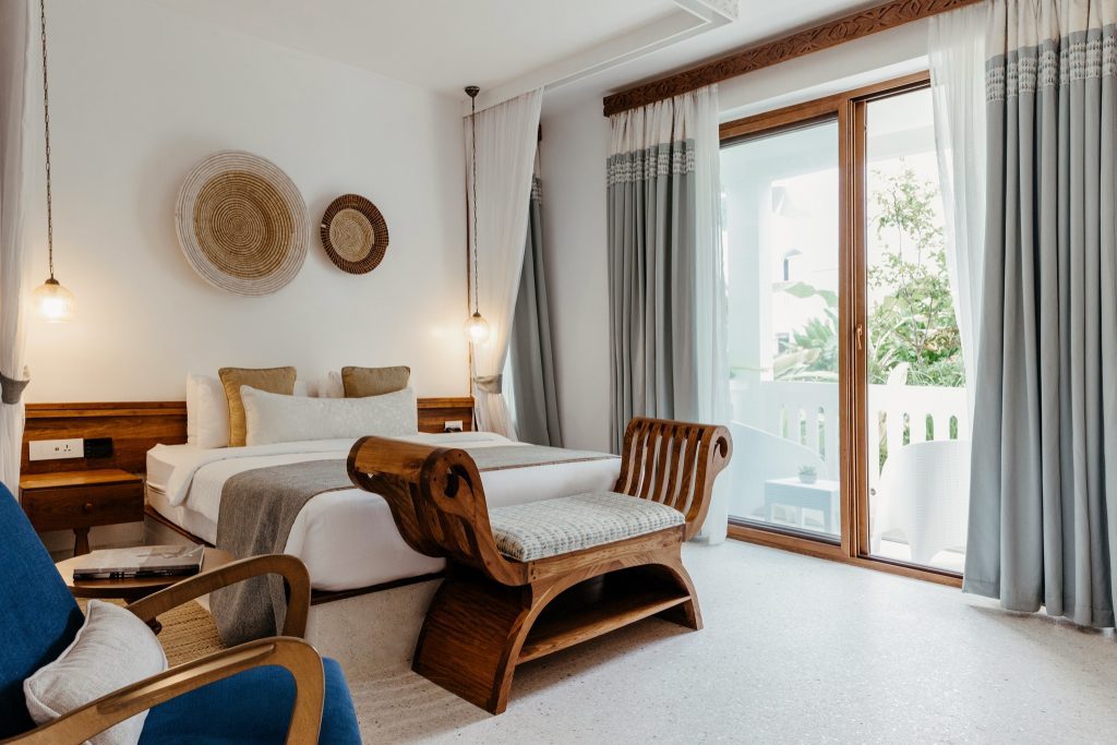 Helles Executive Room Zimmer im Lux Marijani mit großem Bett, Holzbank, blauem Sessel und großer Glasbalkontür