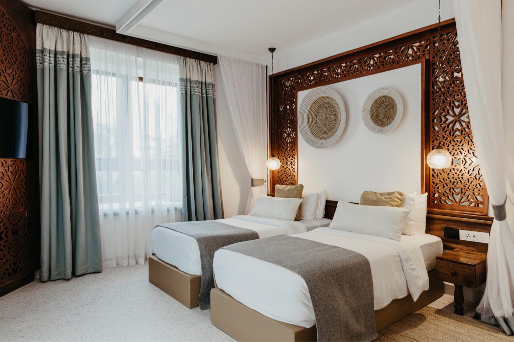 Hotelzimmer Lux Marijani Family Room mit zwei Einzelbetten, weißen Bezügen, grauen Überwürfen und dekorativen Kissen