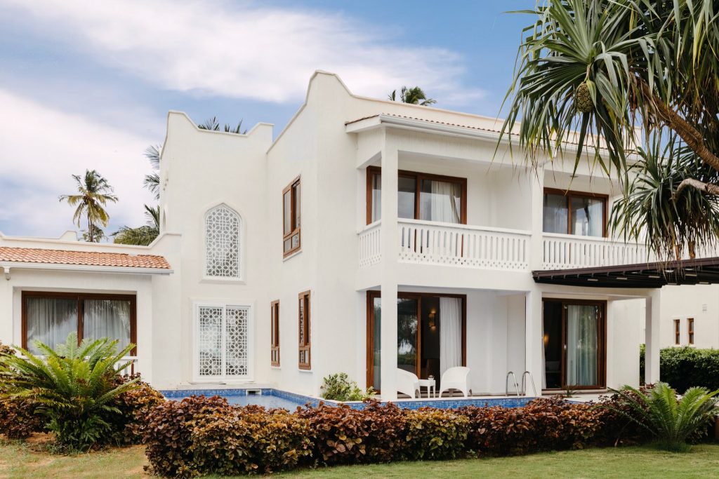 Außenansicht des zweistöckigen Hotels Lux Marijani mit großen Fenstern und Garten in Sansibar