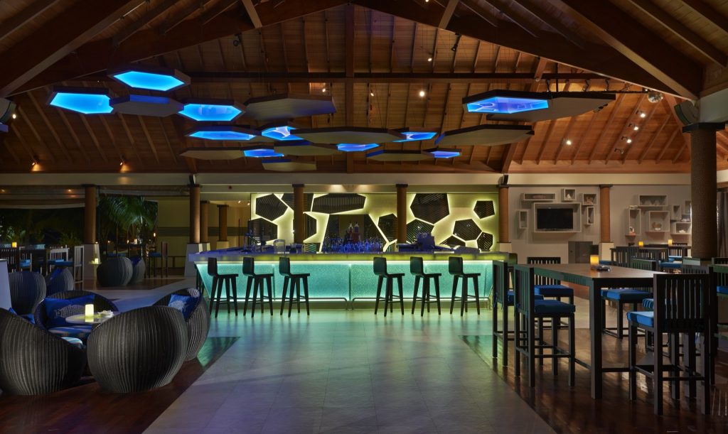 Innenansicht der Bar Lo Brizan im NIVA Labriz Seychelles mit beleuchteter grüner Glastheke und blauen geometrischen Leuchten