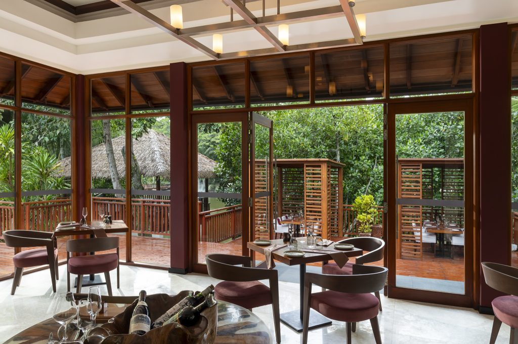 Restaurant Portobello mit modernen Holzmöbeln und weinroten Polsterungen, Panoramafenster mit Blick auf grüne Vegetation