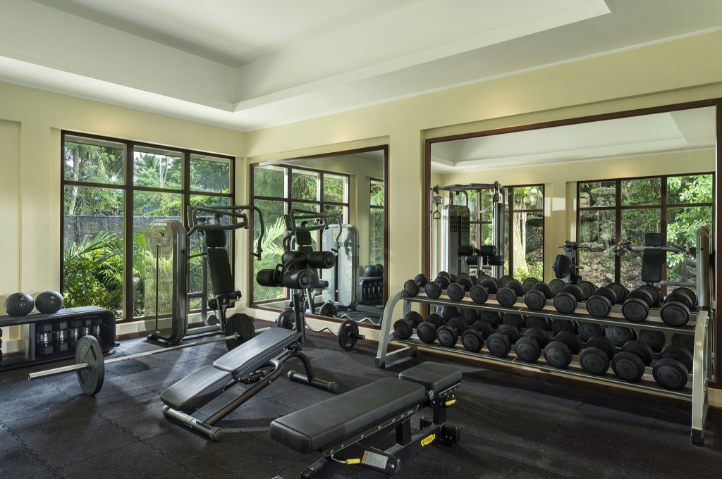 Heller Fitnessraum im NIVA Labriz Seychelles mit Hanteln, Hantelbank, Kraftstation und großem Fenster zum Garten
