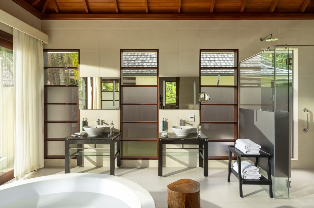 Badezimmer der Beach Sanctuary Pool Villa mit runder Badewanne, Glasdusche und zwei Waschtischen