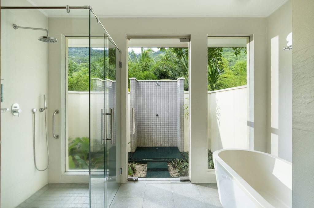 Modernes Badezimmer mit freistehender Badewanne, Glasdusche und Außendusche in der Garden Oasis Pool Villa
