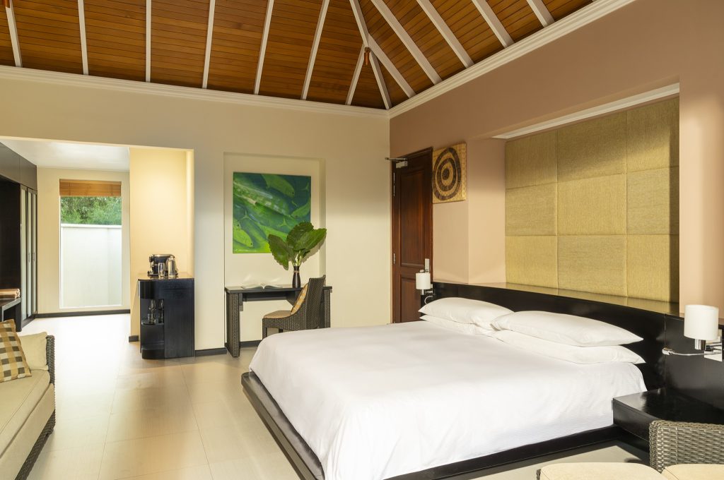 Modern eingerichtetes Schlafzimmer der Garden Oasis Pool Villa mit großem Bett, Tisch und Pflanzen auf den