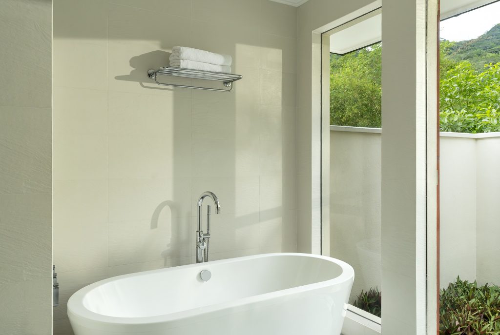 Badezimmer der Garden Villa im NIVA Labriz Seychelles mit freistehender Badewanne, verchromtem Handtuchregal und großem.