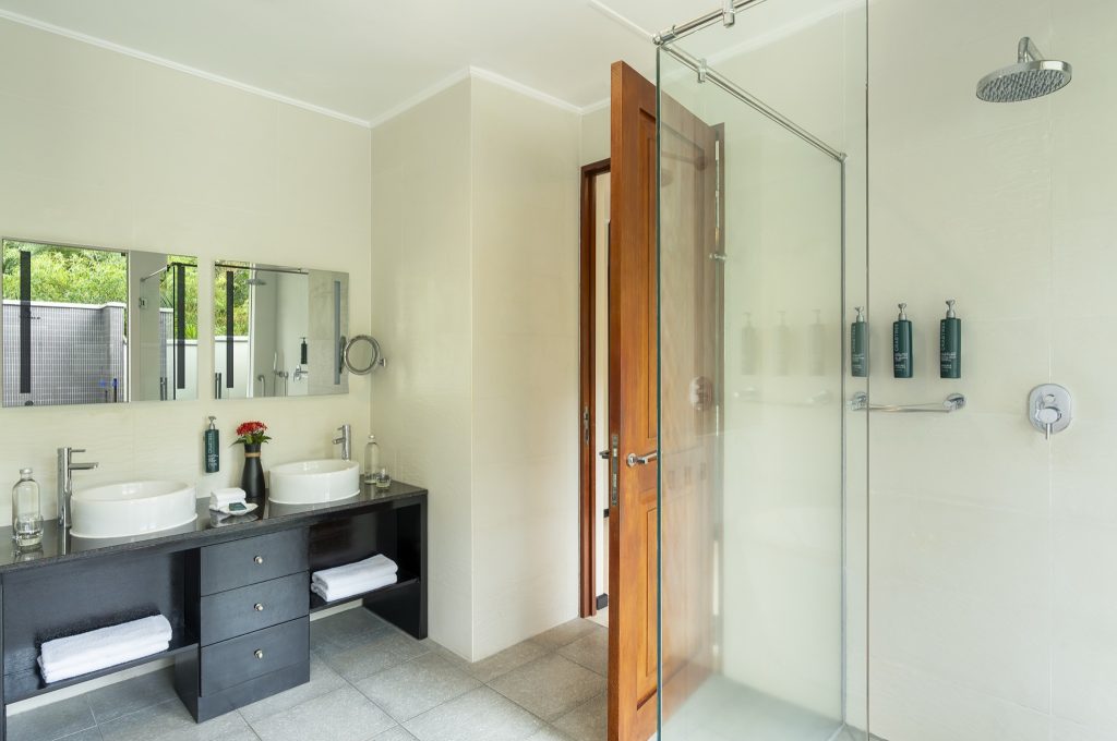 Modernes Badezimmer der Garden Villa im NIVA Labriz Seychelles mit zwei Aufsatzwaschbecken und großer Glasdusche