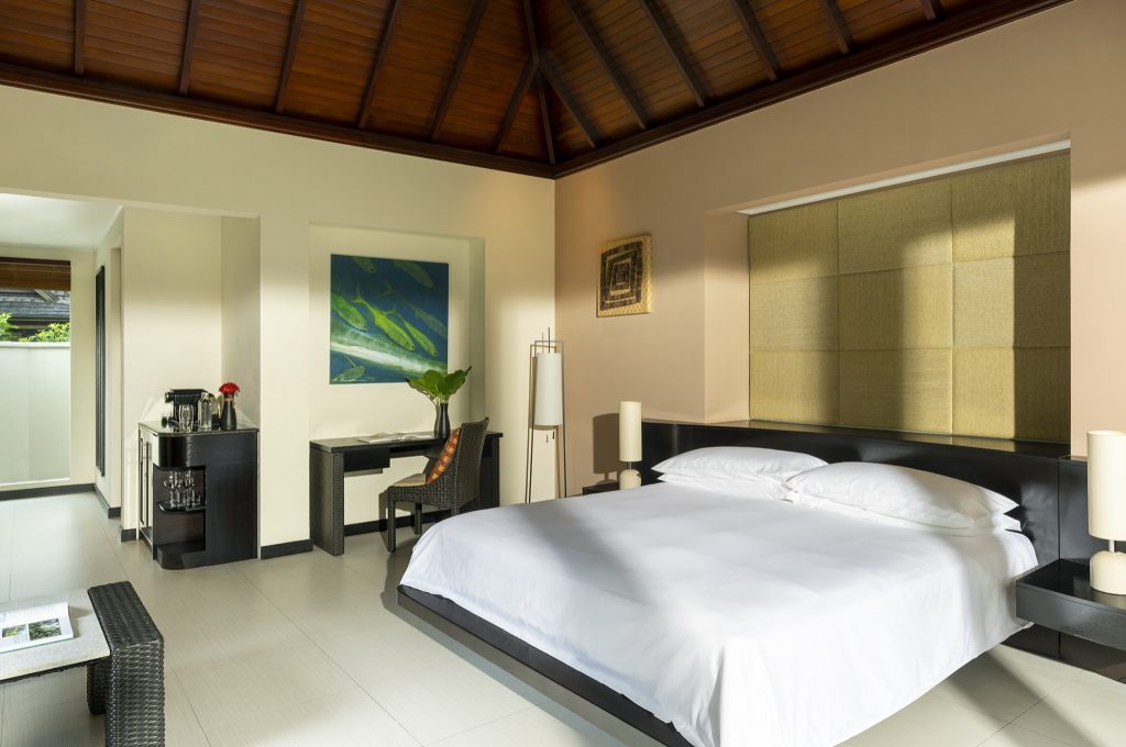 Modernes Hotelzimmer in der Garden Villa mit großem Bett, Nachttischlampen, Schreibtisch und maritimem Bild an der Wand