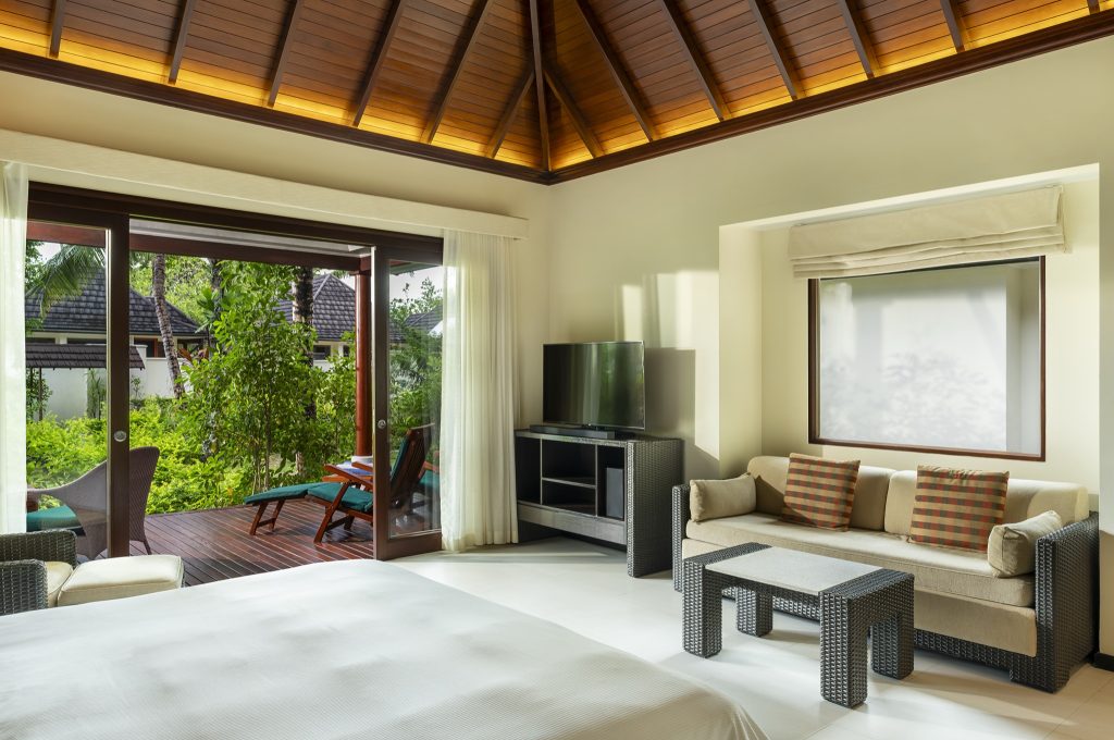 Hotelzimmer Garden Villa mit Bett, Sofa, Flachbildfernseher und großer Glasfront zur Terrasse in den