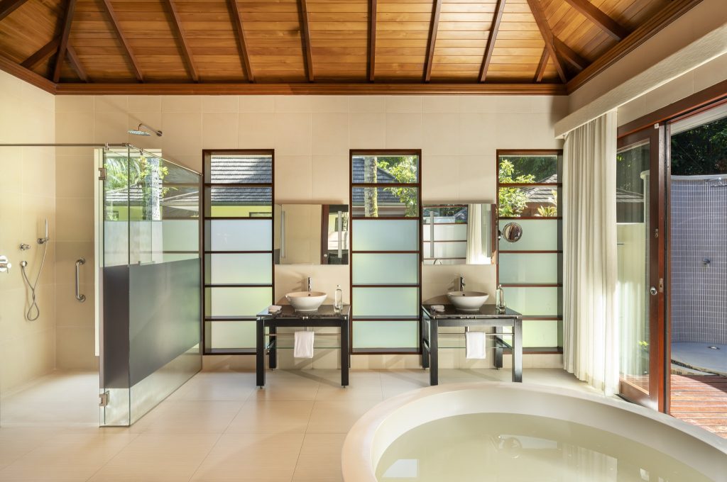 Badezimmer der Jungle Sanctuary Pool Villa mit freistehendem Whirlpool, Holzdecke und Glasdusche in NIVA Labriz Seychelles