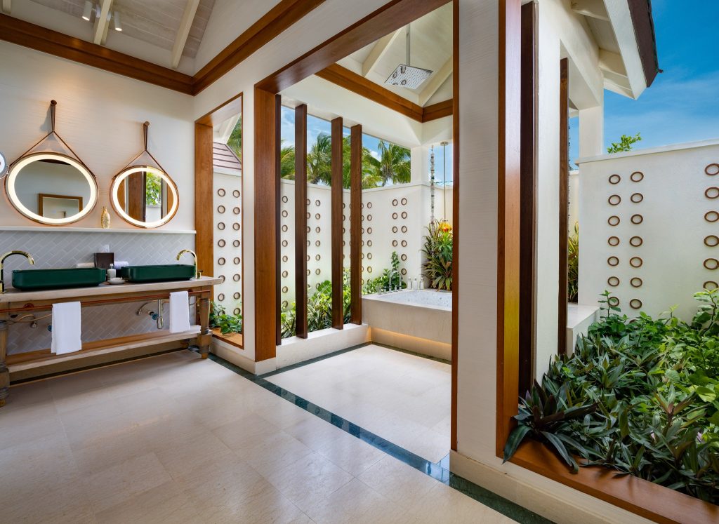 Badezimmer in der Sunnest Beach Pool Villa mit zwei runden Spiegeln, grünen Waschbecken und Badewanne mit Blick ins Grüne