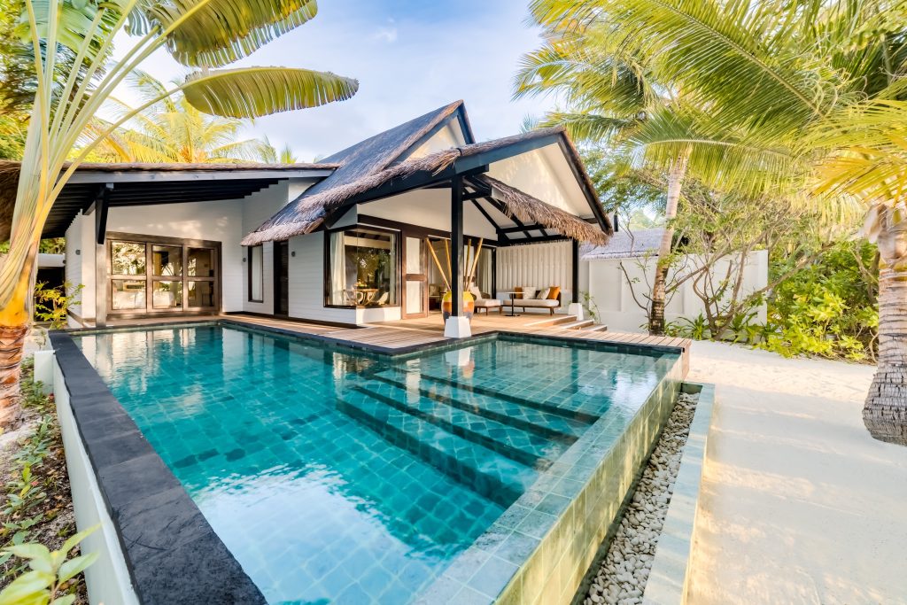 Bungalow-Villa Earth Pool Pavilion mit Schilfdach, weißer Fassade und privatem Pool am Ozen Life Maadhoo Malediven