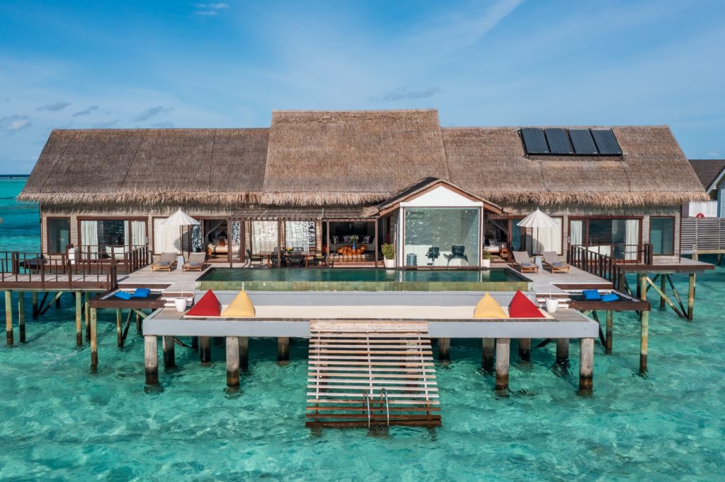 The Ozen Residence Zimmer auf Stelzen über türkisblauem Wasser mit Holzstruktur und Strohdach an der Maledivenlagune