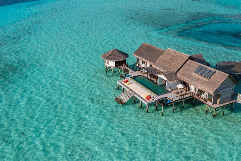 Überwasser-Villa The Ozen Residence mit Strohdächern und Holzterrassen über türkisfarbenem Wasser auf den
