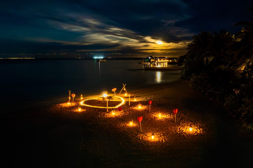 Abendliche Strandkulisse mit Kerzen in Laternen und roten Herzdekorationen am Ozen Reserve Bolifushi