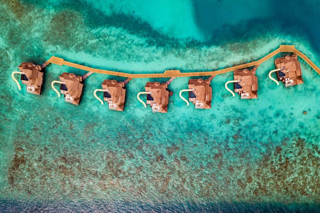 Überwasser-Bungalows Ocean Pool Reserve mit hölzernem Steg und Rutsche, türkisfarbenes Wasser, Malediven