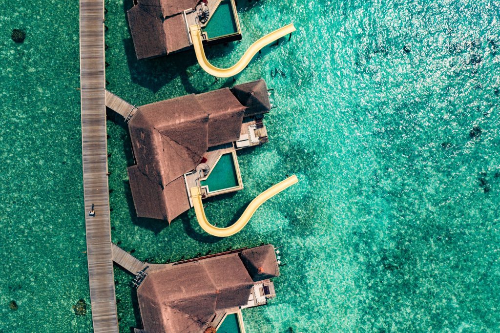 Luftaufnahme der Ocean Pool Suite mit Wasserrutsche über türkisfarbenem Wasser im Ozen Reserve Bolifushi