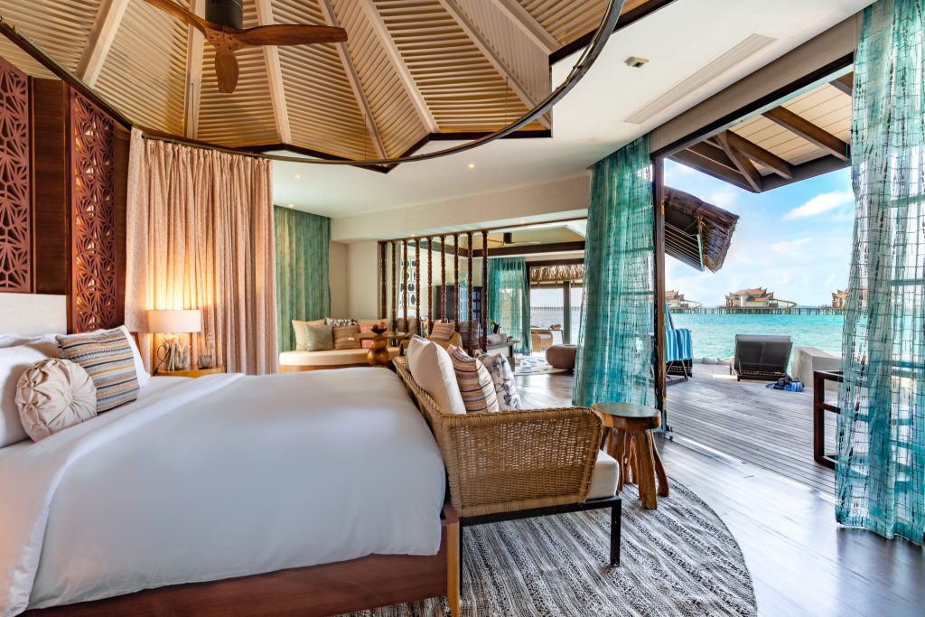 Zimmer der Ocean Pool Suite mit großem Bett, Sitzbereich, Holzbalkendecke und Blick auf Meer und Balkon