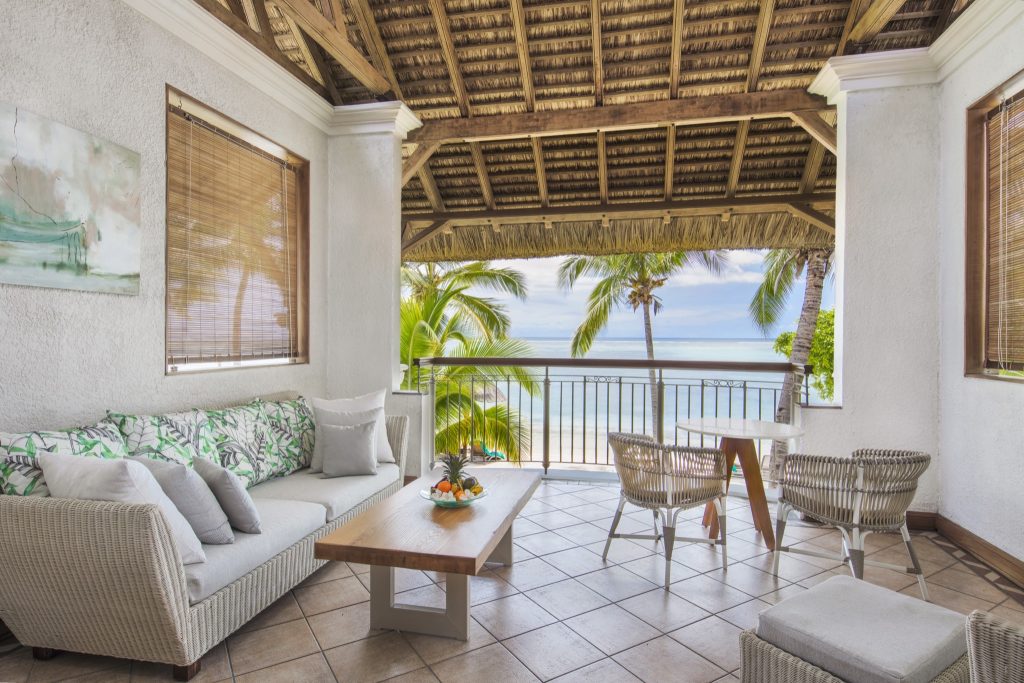 Überdachte Terrasse der Junior Suite mit Rattansofa, Holztisch, geflochtenen Sesseln und Meerblick auf Mauritius
