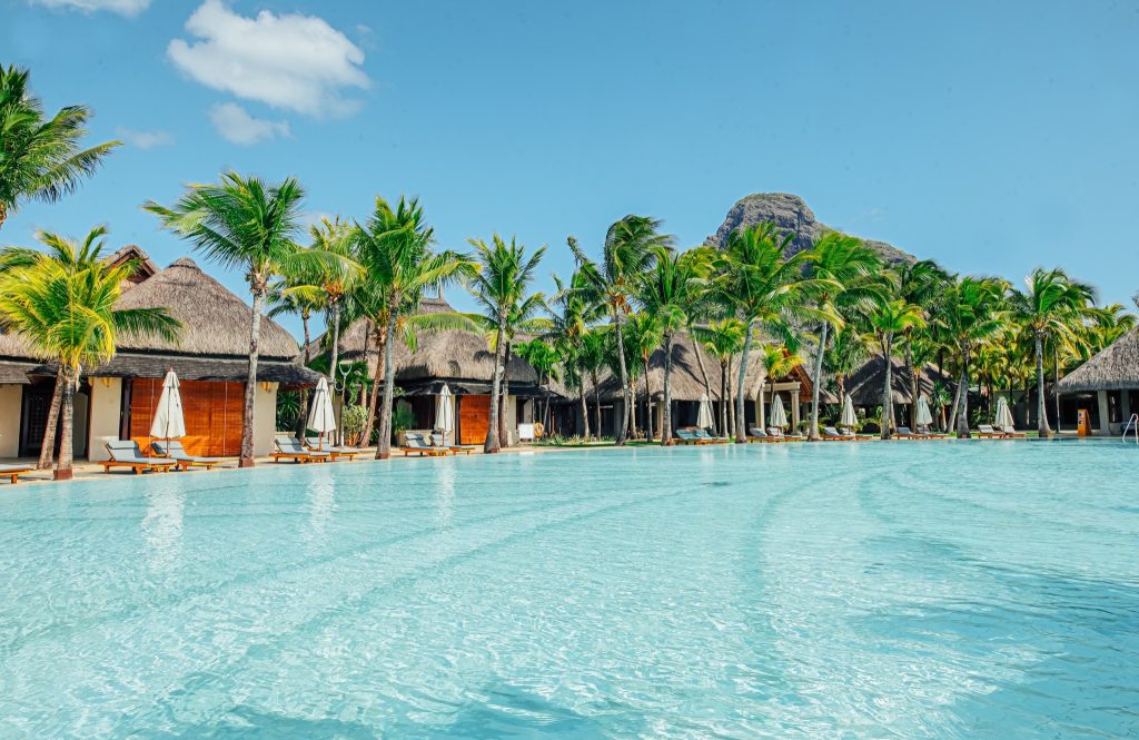 Großer Swimmingpool mit reetgedeckten Bungalows und Palmen im Paradis Beachcomber Golf Resort & Spa Mauritius