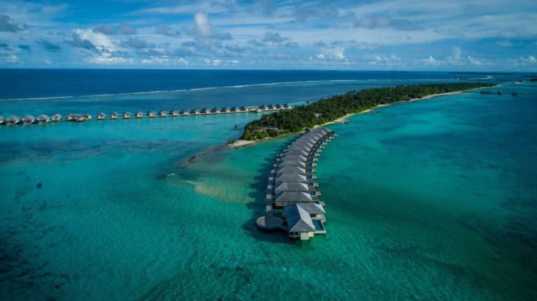 Luftaufnahme der Überwasserbungalows in einer langen Reihe über türkisfarbener Lagune