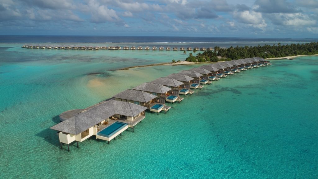 Reihe von Überwasser-Bungalows mit Schilfdächern über türkisfarbenem Meer