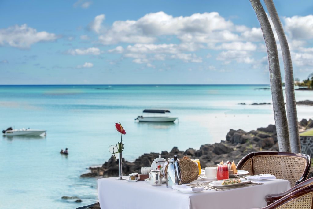 Frühstückstisch mit weißer Tischdecke und Rattanstühlen am Meer im Restaurant Goelette auf Mauritius