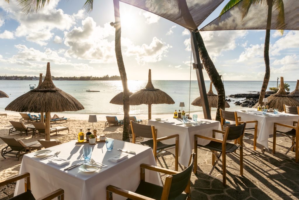 Strandrestaurant Grand Sable mit weißen Tischdecken, blauen Gläsern und Blick auf Strand und Meer in Mauritius
